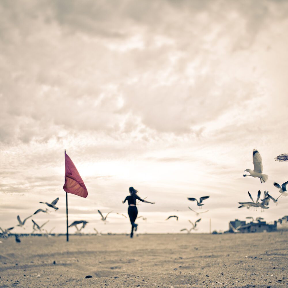 Woman running through a flock of seagulls
